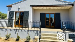 A two-story house with a balcony, a wooden door, and a small garden area. - La Ceriseraie - TRAUSSE (TRAUSSE)