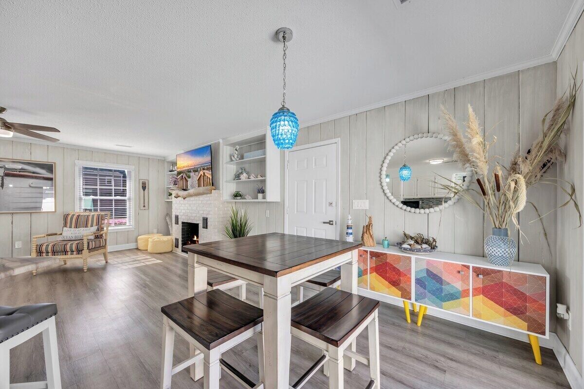 Una sala de estar moderna con una mesa de comedor de madera, armarios blancos y un aparador de diseño geométrico y colores vivos.