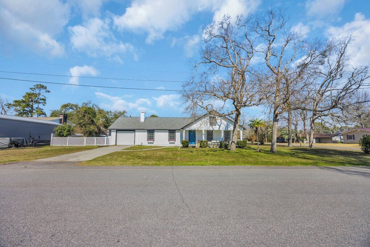 A residential house with a front yard, a driveway, and a clear sky.