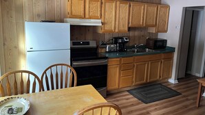Una cocina con armarios de madera, un refrigerador, una estufa, un microondas y un lavabo.