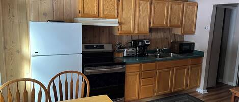 A kitchen with wooden cabinets, a refrigerator, a stove, a microwave, and a sink.
