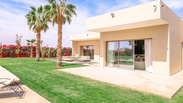 Une maison moderne à deux étages, dotée d’un patio, de grandes portes-fenêtres coulissantes et d’une pelouse bien entretenue.