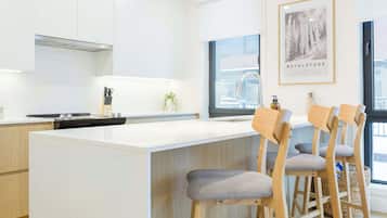 A modern kitchen with a central island, wooden bar stools, and a large window providing natural light.
