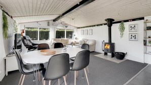 A modern living room with a central fireplace, a dining area with a white table and black chairs, and a cozy seating area with a sofa and a TV. - Stunning home in Sydals with WiFi (Sydals)