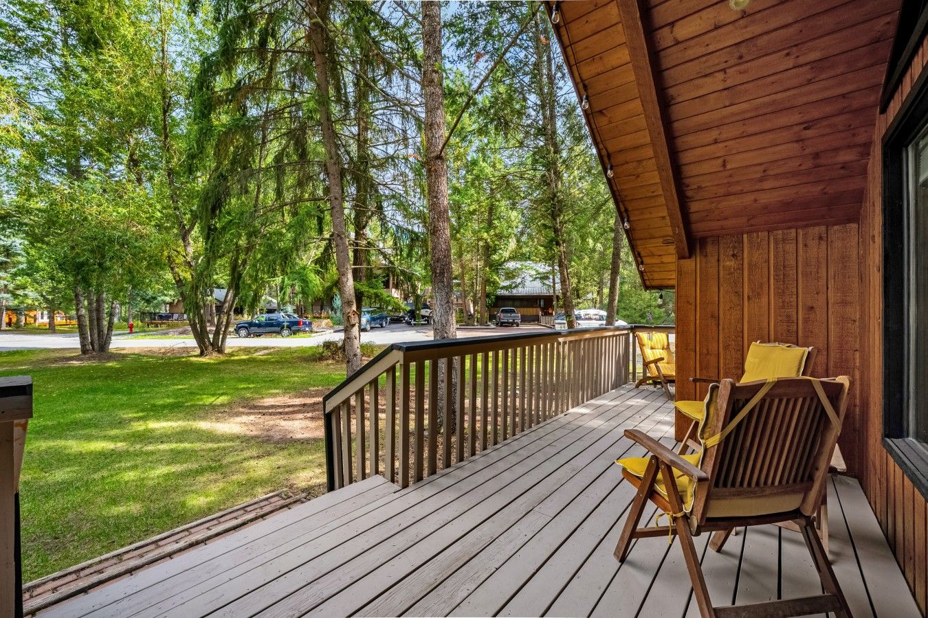 Une terrasse en bois avec une rambarde, deux chaises et une table.