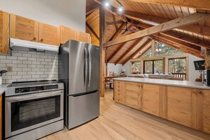 A modern kitchen with stainless steel appliances, wooden cabinets, and a large island.