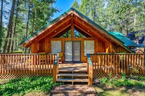 A wooden cabin with a porch, a door, and a window.