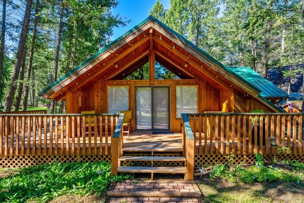A wooden cabin with a porch, a door, and a window.