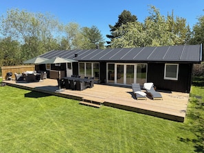 A modern house with a deck, outdoor furniture, and a barbecue grill. - Bright holiday home with sunny terrace (Væggerløse)