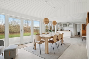 A modern kitchen with white cabinets, a microwave, and a wooden island. - Bright holiday home with sunny terrace (Væggerløse)