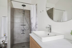 A modern bathroom with a shower, a sink, and a mirror. - Bright holiday home with sunny terrace (Væggerløse)