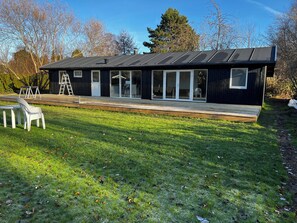 A modern house with a deck, a ladder, and a chair. - Bright holiday home with sunny terrace (Væggerløse)