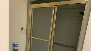 Casa de banho com sanita, cabine de duche e rolo de papel higiénico.