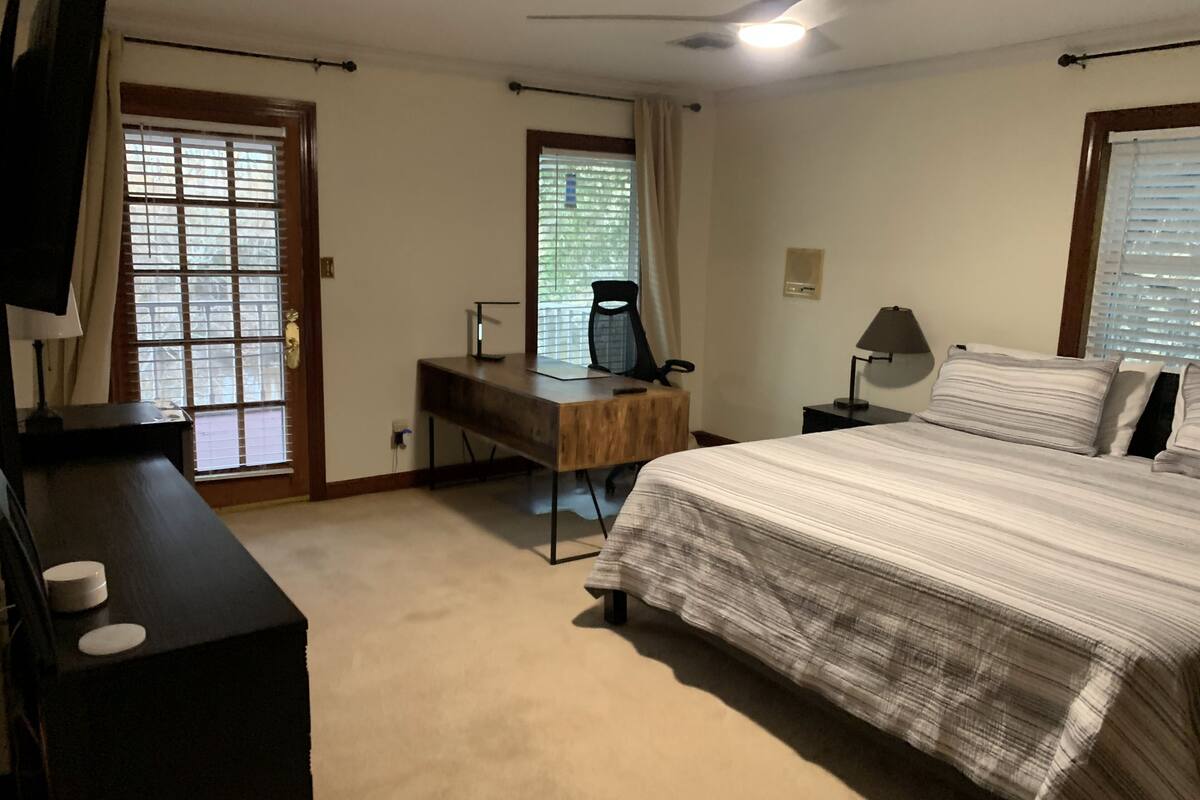 A bedroom with a bed, desk, chair, and a ceiling fan.