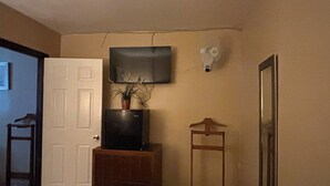 A room with a bed, a television mounted on the wall, a small wooden cabinet, and a mirror. - Motel del Bosque (Tijuana)