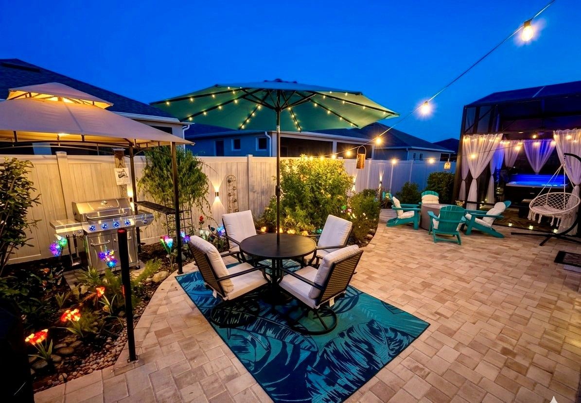An outdoor patio area with a round table and chairs, a barbecue grill, and string lights.
