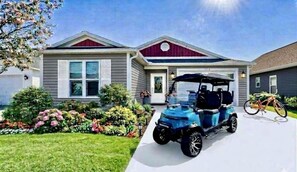 A residential house with a driveway, a golf cart, and a bicycle. - Luxury Oasis: Golf Cart, Hot Tub, Private Lanai (The Villages)