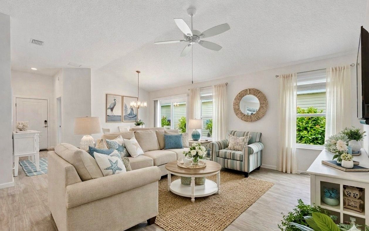 Ein Wohnzimmer mit Deckenventilator, einer Couch, einem Couchtisch und einem Fernseher.