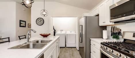 A modern kitchen with stainless steel appliances, a central island with a sink, and a built-in oven.