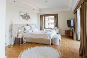 A modern bedroom with a large bed, a TV, and a view of the city through the window. - 2-bedroom apartment at St Regis T1 - Dhb Stays (Cairo Governorate)