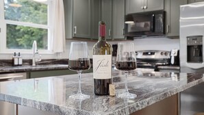 Une cuisine avec un plan de travail en marbre, une bouteille de vin et deux verres de vin rouge.