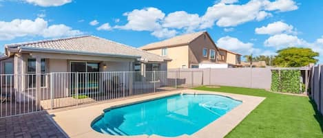 A residential property with a swimming pool, a fenced patio, and a well-maintained lawn.