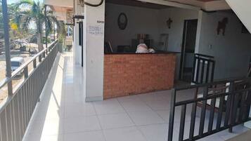Zona de recepción con mostrador de ladrillo, un reloj y una cruz en la pared.