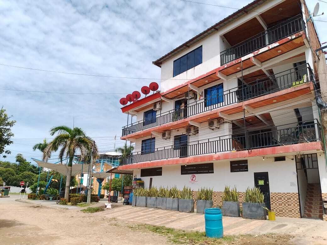 A multi-story building with balconies, a parking sign, and a palm tree.
