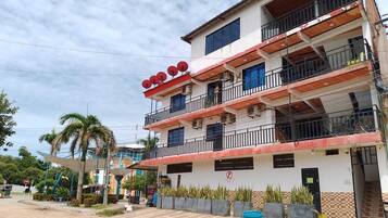 A multi-story building with balconies, a parking sign, and a palm tree.