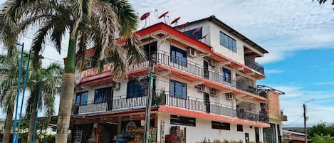 A multi-story building with balconies, satellite dishes, and a commercial ground floor.