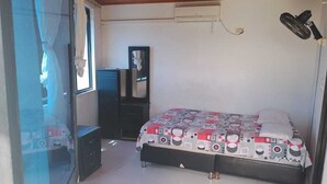 A bedroom with a bed, a dresser, a mirror, and an air conditioning unit. - Hotel Volga (Puerto Lopez)