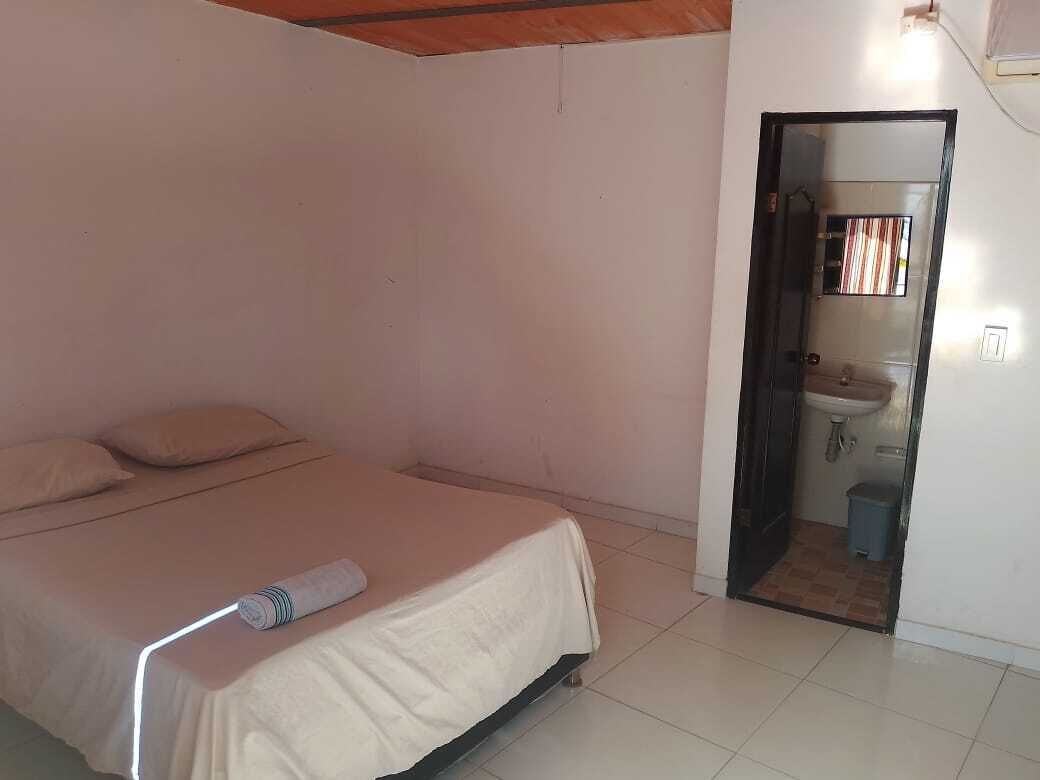 A bedroom with a bed, a bedside table, and a bathroom visible through an open door.