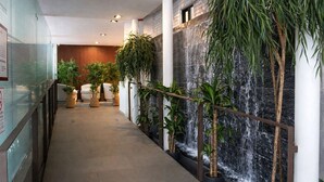 Un couloir agrémenté d’une cascade, de plantes en pot et d’un espace détente avec des coussins.