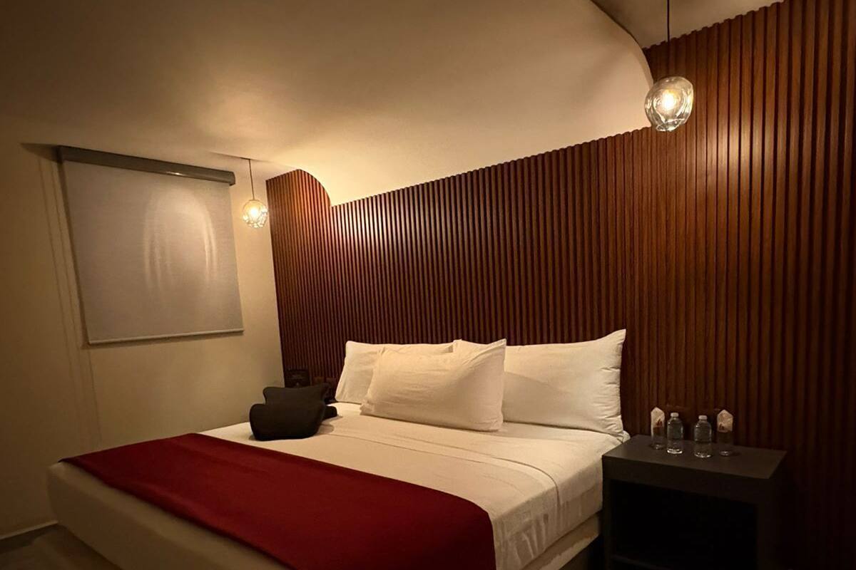 Une chambre moderne avec un lit, des tables de chevet et un luminaire fixé au mur.