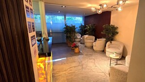 Un hall d’entrée avec un comptoir de réception, un espace détente et des plantes en pot.
