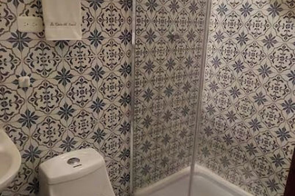 A bathroom with patterned tiles, a toilet, and a towel hanging on the wall.