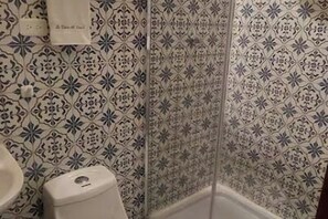Un baño con azulejos estampados, un inodoro y una toalla colgada en la pared.
