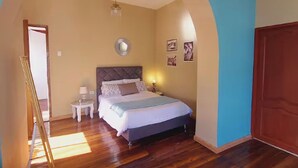 A bedroom with a bed, a nightstand, a lamp, and a mirror on the wall. - The Colonel's House (Quito)