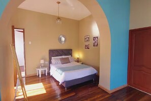 Un dormitorio con una cama, una mesita de noche, una lámpara y un espejo en la pared.