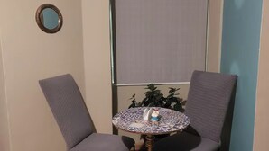 A small room with two grey upholstered chairs and a round table with a patterned tablecloth. - The Colonel's House (Quito)