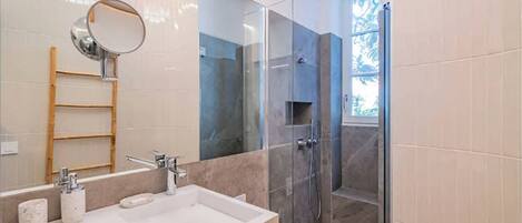 Un baño moderno con un lavamanos amplio, espejo y zona de ducha.