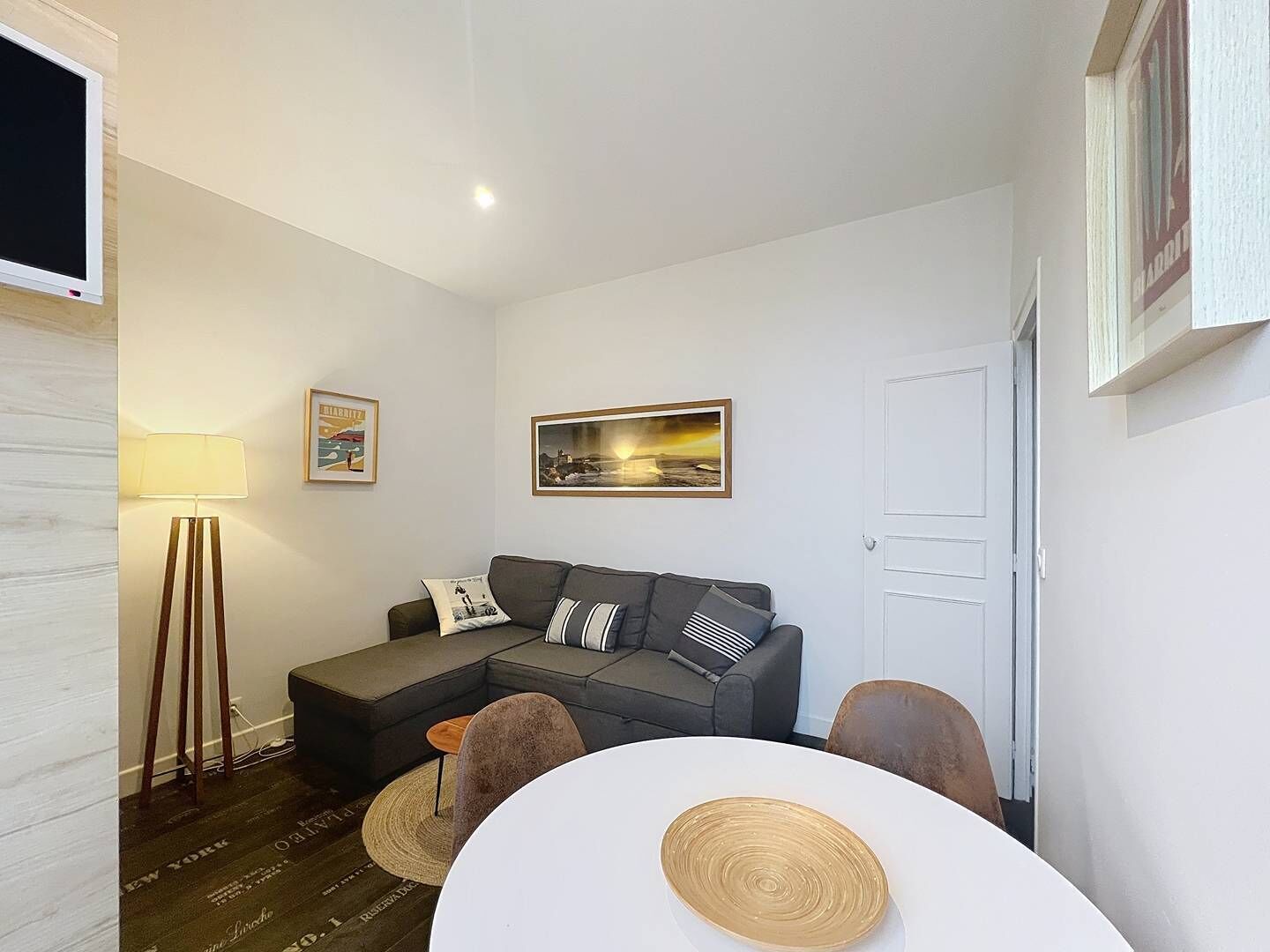 Un salon moderne avec un canapé gris, une table ronde blanche et un lampadaire.