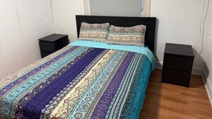 A bedroom with a bed, two bedside tables, a wardrobe, and a wall-mounted air conditioner.