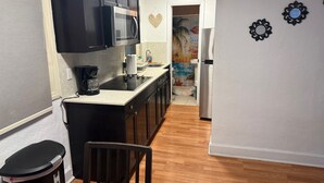 A compact kitchen with dark cabinets, a microwave, a coffee maker, and a refrigerator.
