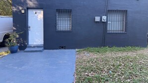 A building with a dark exterior, a white door, and two windows with metal bars.