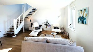 Ein geräumiges Wohnzimmer mit Treppe, einer Couch, einem Couchtisch und einem Gemälde an der Wand.