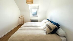 Ein Schlafzimmer mit Bett, einer Pendelleuchte, einem Fenster und einer Heizung.