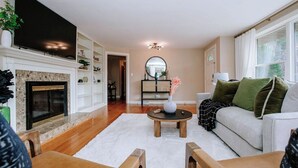Una sala de estar con chimenea, televisor de pantalla plana, sofá y mesa de centro.