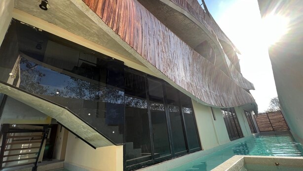 Un edificio moderno con piscina, ampie finestre e un pontile in legno.