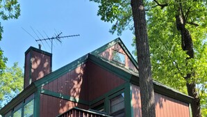 Une cabane en bois à deux étages, dotée d’un balcon et entourée d’arbres.